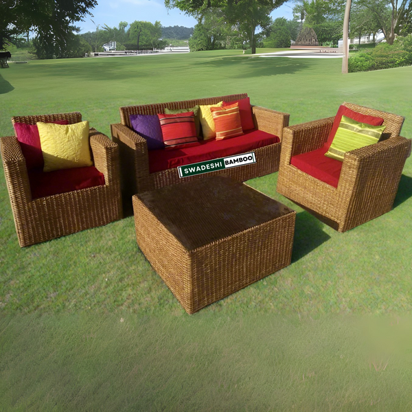Outdoor wicker furniture set with colorful cushions on a grassy area, featuring the Swadeshi Bamboo brand.