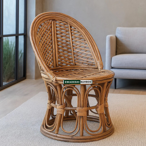 A round rattan accent chair with a high curved backrest, shown in a modern living room setting. The chair is made of natural brown woven rattan with a green and white 'SWADESHI BAMBOO' label on the seat.