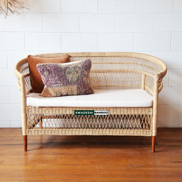 Wicker bench with cushions against a white tiled wall