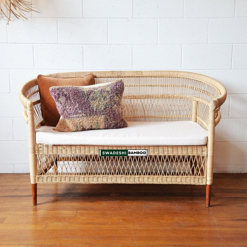 Wicker bench with cushions against a white tiled wall
