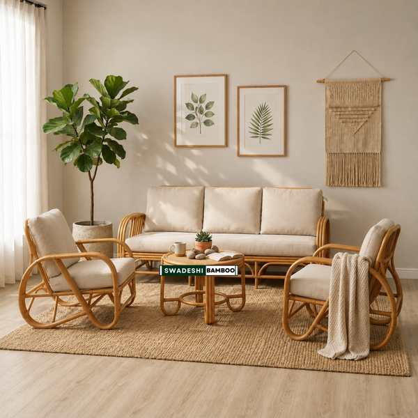 A bohemian-style rattan furniture set in a warm, sunlit living room. The set includes a three-seater sofa, two matching armchairs, and a coffee table, all constructed from light natural rattan with thick cream cushions.