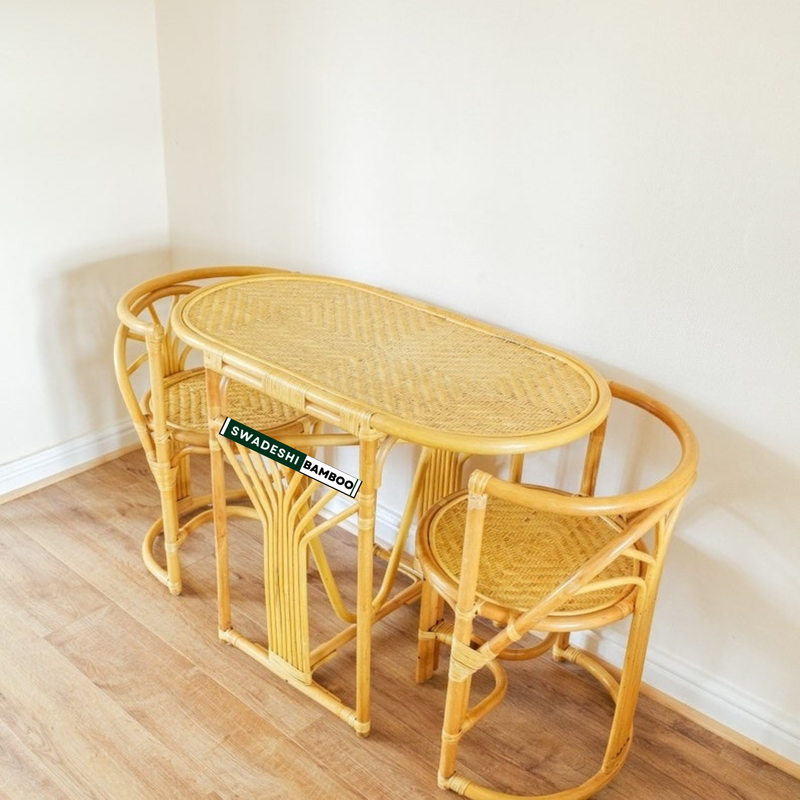 Wicker dining set with table and chairs on a wooden floor against a white wall.